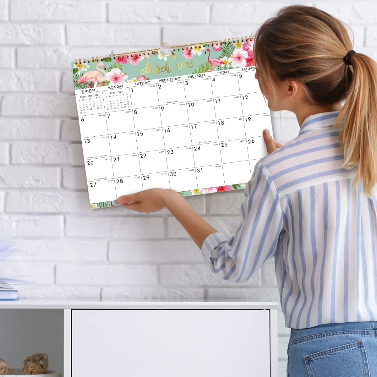 Woman placing a floral calendar on a wall